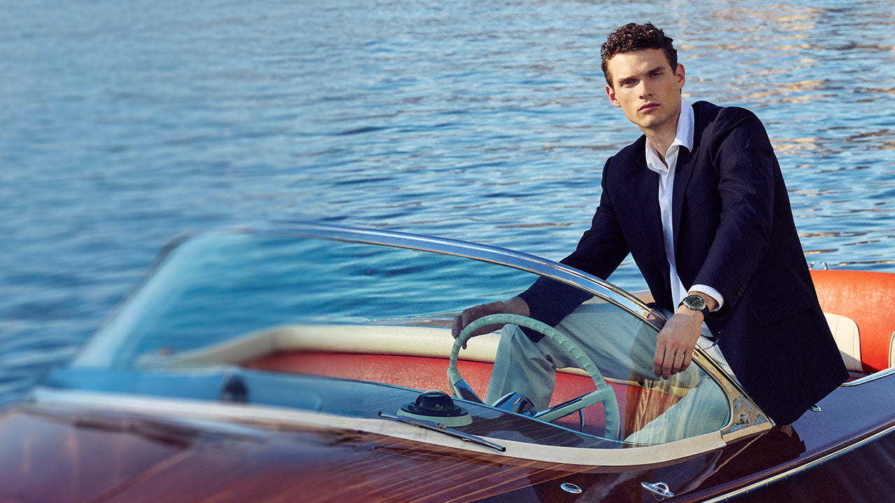 Model wearing the Q Timex® Continental Chronograph while seated in a classic speedboat on the water.