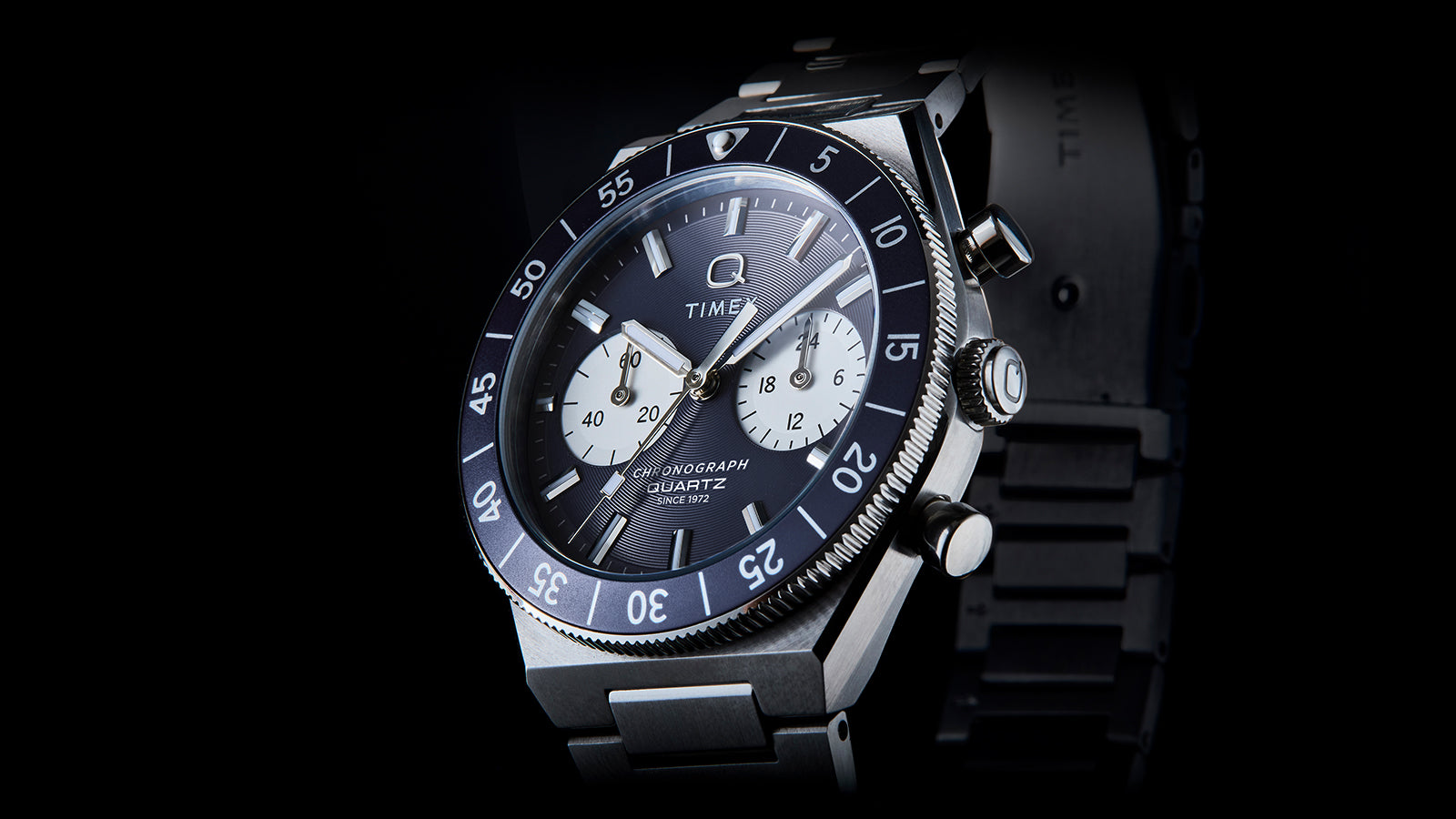 Angled close-up of the Q Timex Continental Chronograph highlighting the blue dial, black rotating bezel, and chronograph pushers.