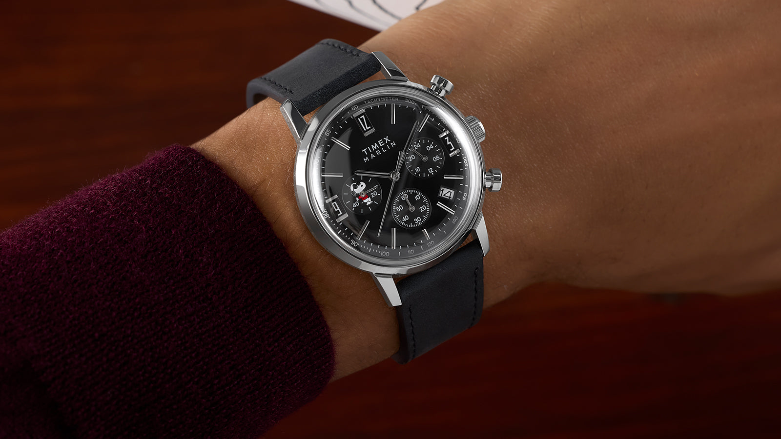 Side view of the Peanuts® x Timex Marlin® Chronograph Joe Cool watch worn on a wrist, highlighting the black dial, chronograph subdials, and polished stainless steel case.