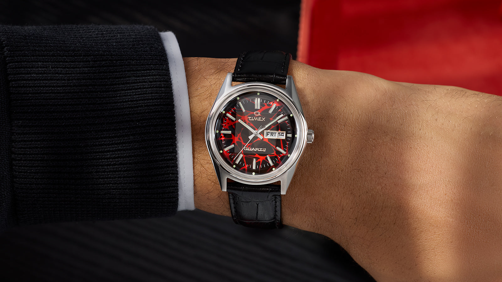 Alternate on-wrist view of the Q Timex® Red Vega 1978 Reissue watch with red patterned dial and black leather strap.