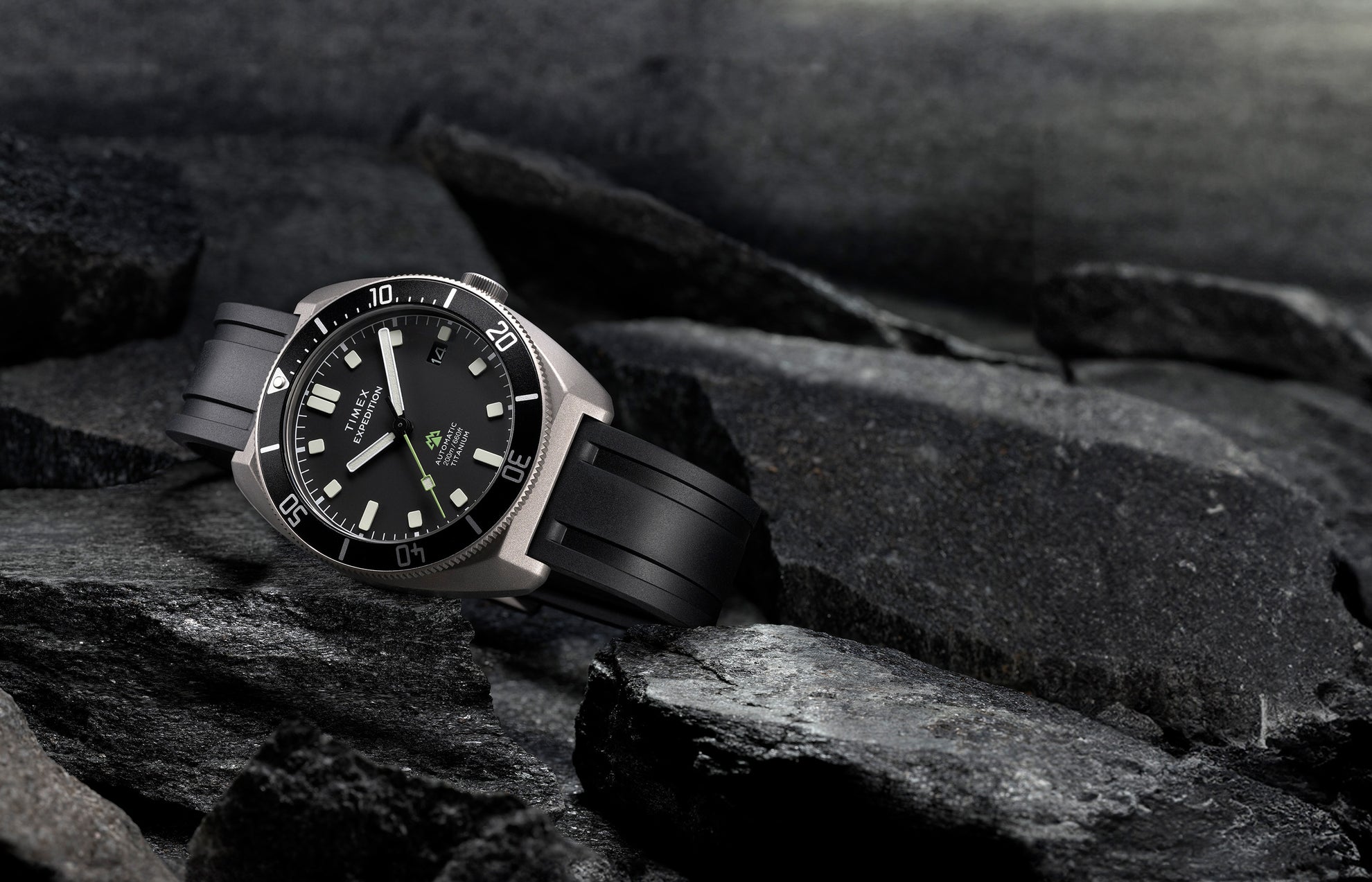 Timex Expedition Pioneer Titanium Automatic watch with black dial and rubber strap placed on rugged rocks