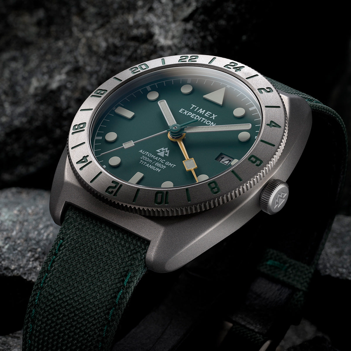 Close-up of Timex Expedition Pioneer Titanium Automatic GMT showing green dial, luminous markers, and GMT bezel.