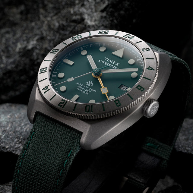 Close-up of Timex Expedition Pioneer Titanium Automatic GMT showing green dial, luminous markers, and GMT bezel.