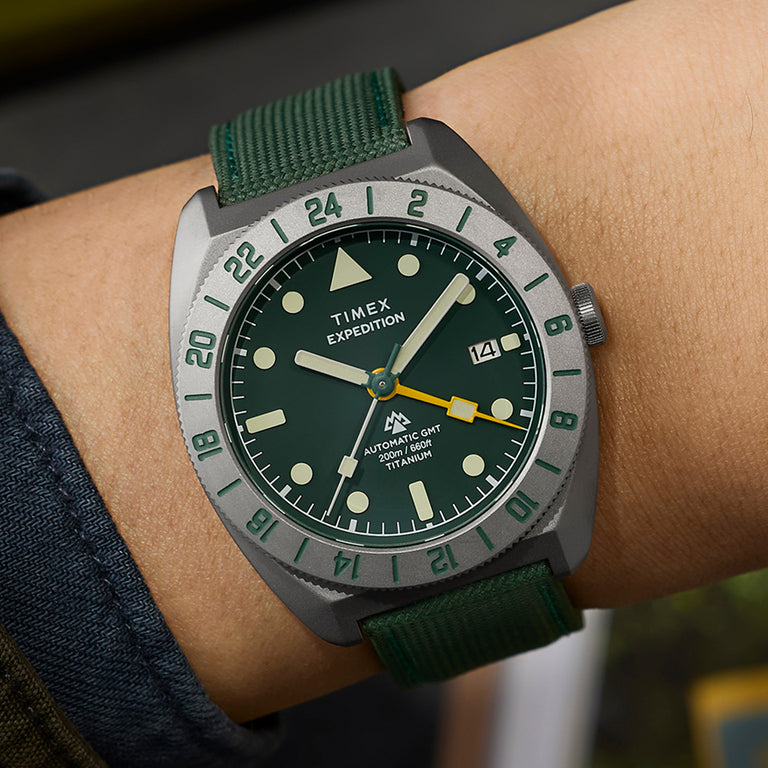 Timex Expedition Pioneer Titanium Automatic GMT watch worn on wrist with green fabric strap and bold outdoor styling.