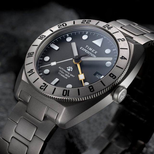 Close-up angled view of the Expedition® Pioneer Titanium Automatic GMT highlighting the black dial, luminous hour markers, date window, and yellow GMT hand.