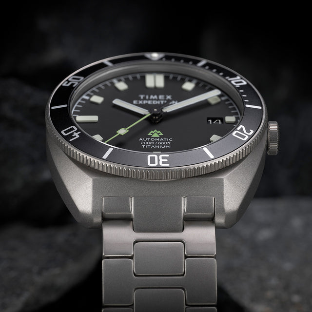 Angled close-up of the Expedition® Pioneer Titanium Automatic showcasing the matte titanium case, bold luminous markers, and “Automatic 200m/660ft Titanium” text.
