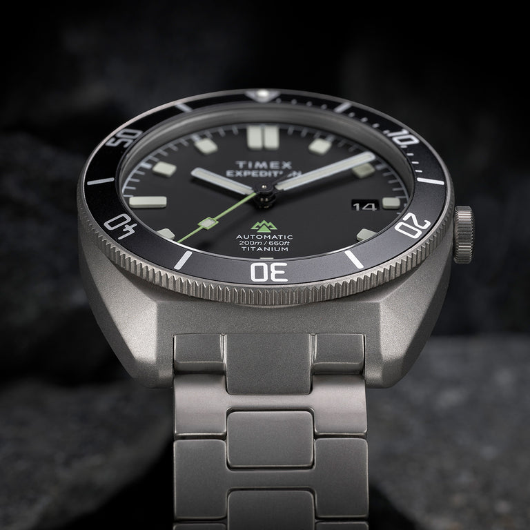 Angled close-up of the Expedition® Pioneer Titanium Automatic showcasing the matte titanium case, bold luminous markers, and “Automatic 200m/660ft Titanium” text.
