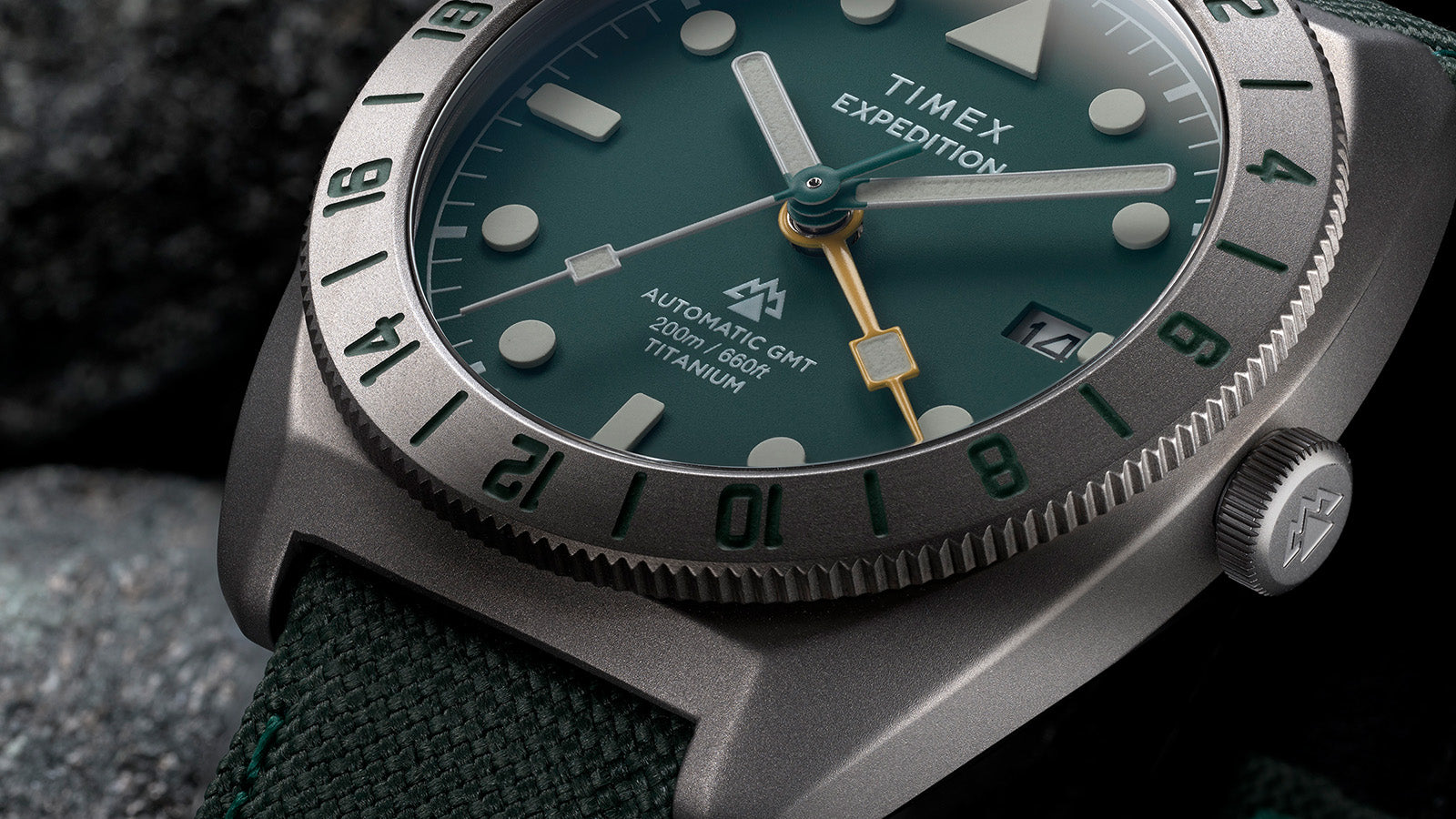 Detailed view of green dial with luminous indices, yellow GMT hand, and date window on Timex Expedition watch.