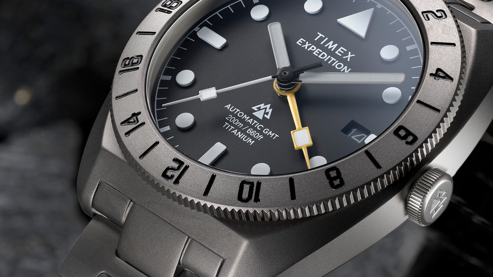 Macro close-up of the dial displaying “Automatic GMT 200m/660ft Titanium” text, bold indices, and yellow GMT hand.