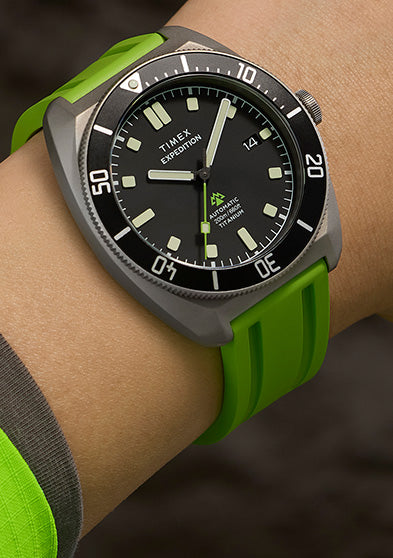 Expedition® Pioneer Titanium Automatic watch worn on the wrist, featuring a matte titanium case, black dial, and bright green rubber strap.