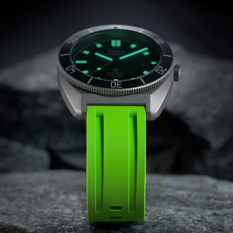 Low-light close-up of the Expedition® Pioneer Titanium Automatic showing luminous hands and hour markers glowing against the black dial.