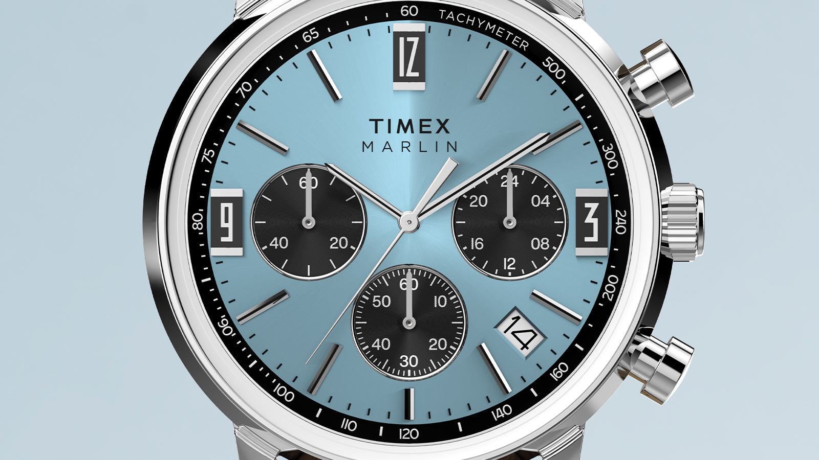 Close-up of the Timex Marlin Chronograph Tachymeter dial with a light blue sunray finish, black chronograph subdials, tachymeter scale, and date window.