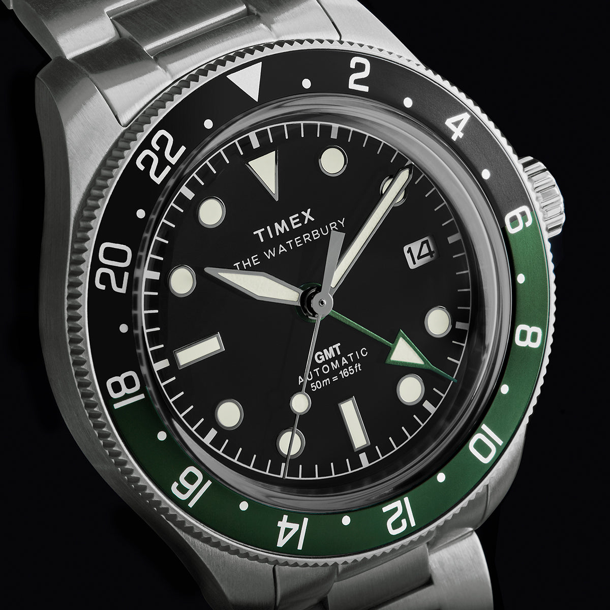 Close-up of Timex Waterbury Heritage Automatic GMT watch featuring black dial and green-black bezel.