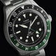 Close-up of Timex Waterbury Heritage Automatic GMT watch featuring black dial and green-black bezel.