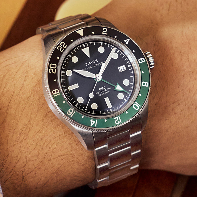 Timex Waterbury Heritage Automatic GMT watch worn on wrist with stainless steel bracelet and black dial.