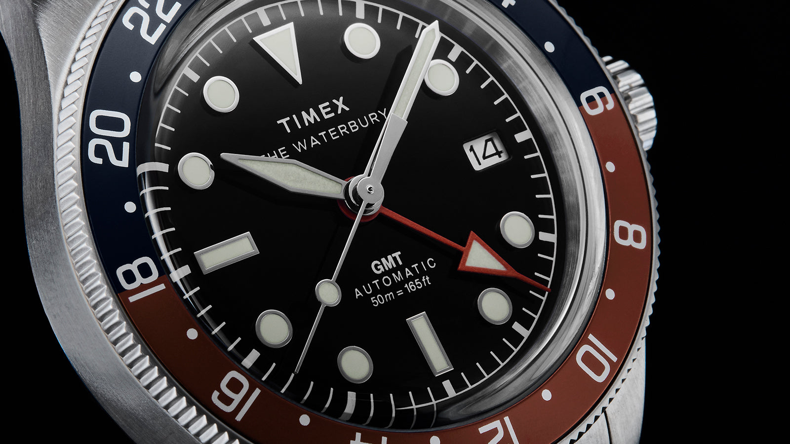 Detailed view of Timex Waterbury GMT automatic watch dial with luminous markers and GMT hand.