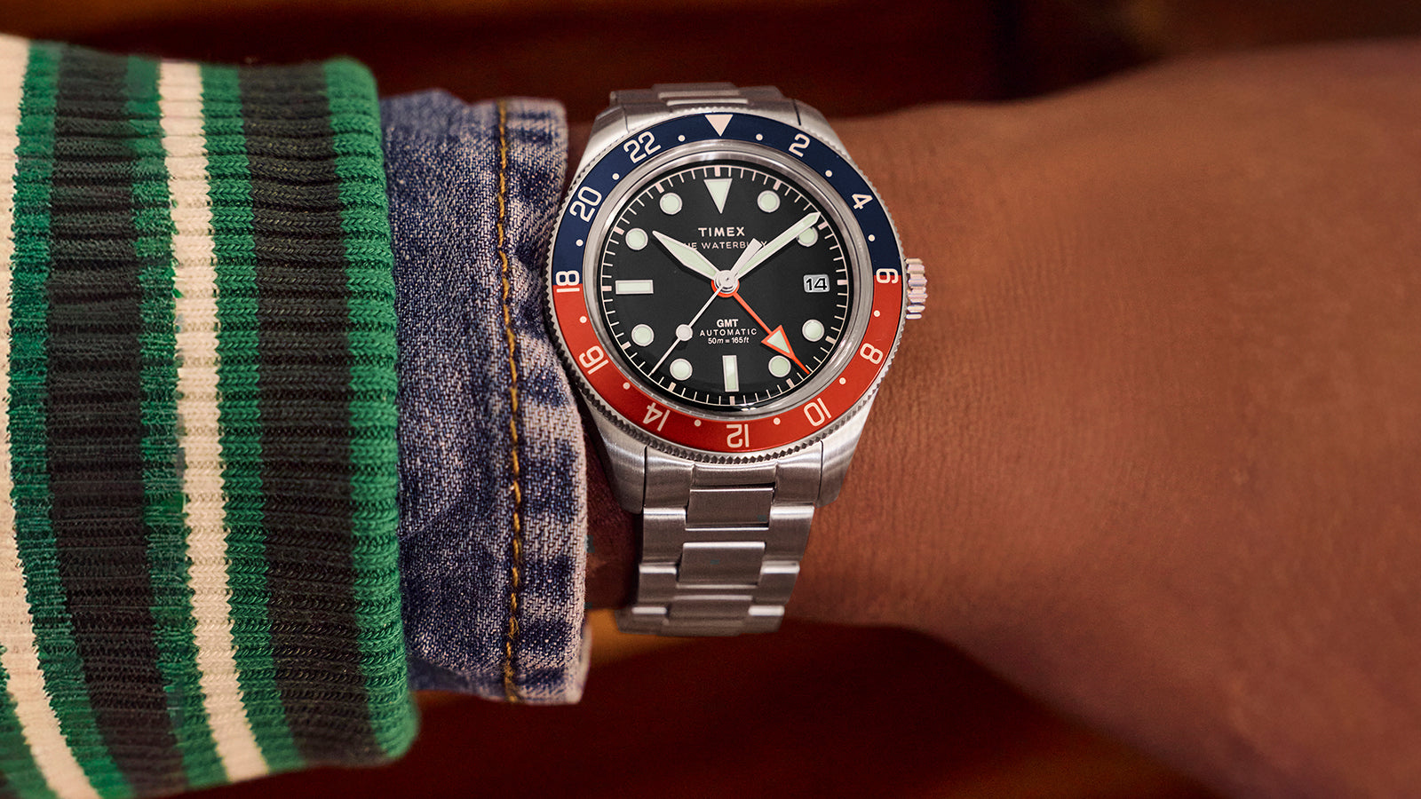 Timex Waterbury GMT automatic watch worn on wrist with stainless steel bracelet and black dial.