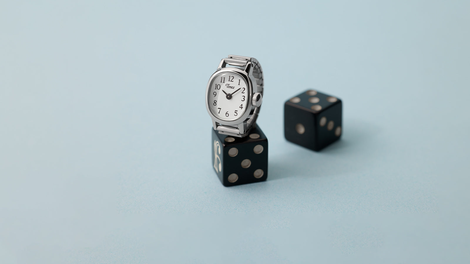 Angled view of Timex Cavatina® Mini watch with polished silver-tone case and flexible metal expansion band on black dice.