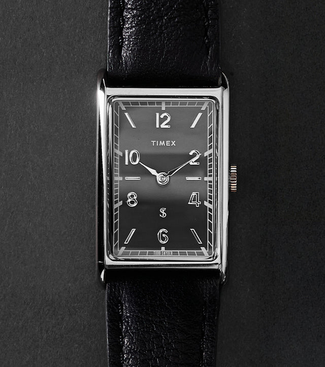 Timex x Todd Snyder 1976 Lexington rectangular watch with a black dial and black leather strap displayed vertically on a dark background
