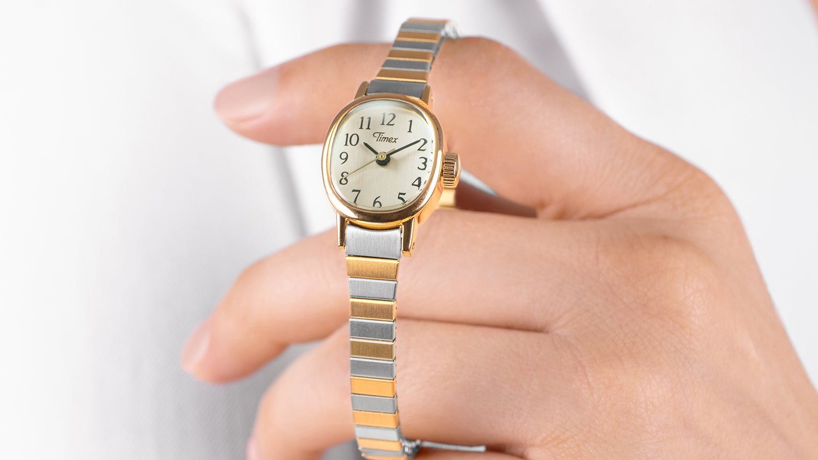 Cavatina® Mini women’s watch worn on wrist, highlighting the petite gold-tone case and flexible two-tone expansion bracelet.