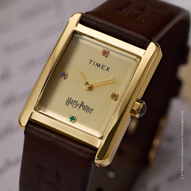 Close-up of Harry Potter x Timex Hailey Hogwarts gold-tone dial with house-colored crystal hour markers and brown leather strap.