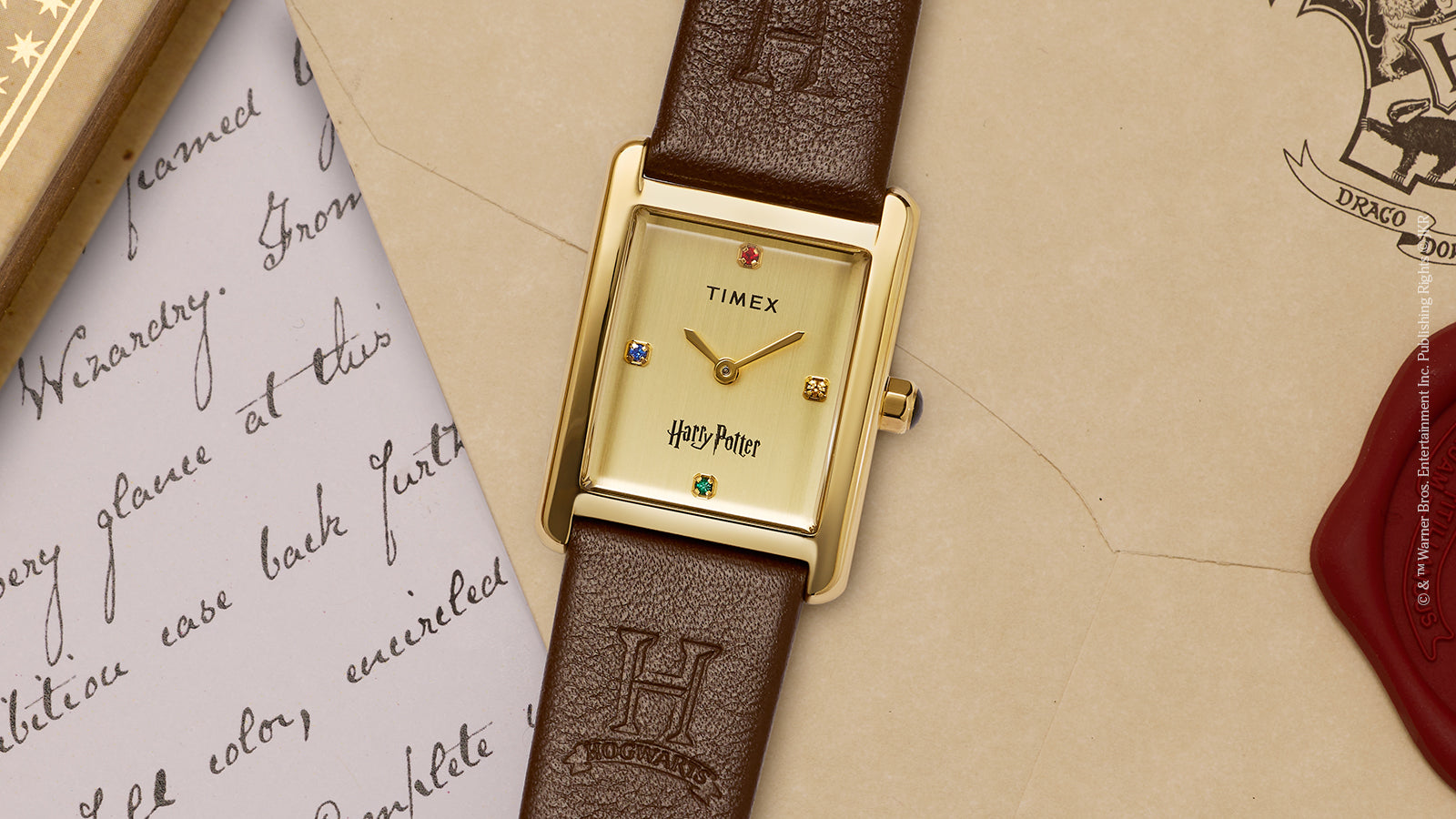 Harry Potter x Timex Hailey Hogwarts rectangular watch featuring gold-tone case and embossed Hogwarts “H” logo on brown leather strap.