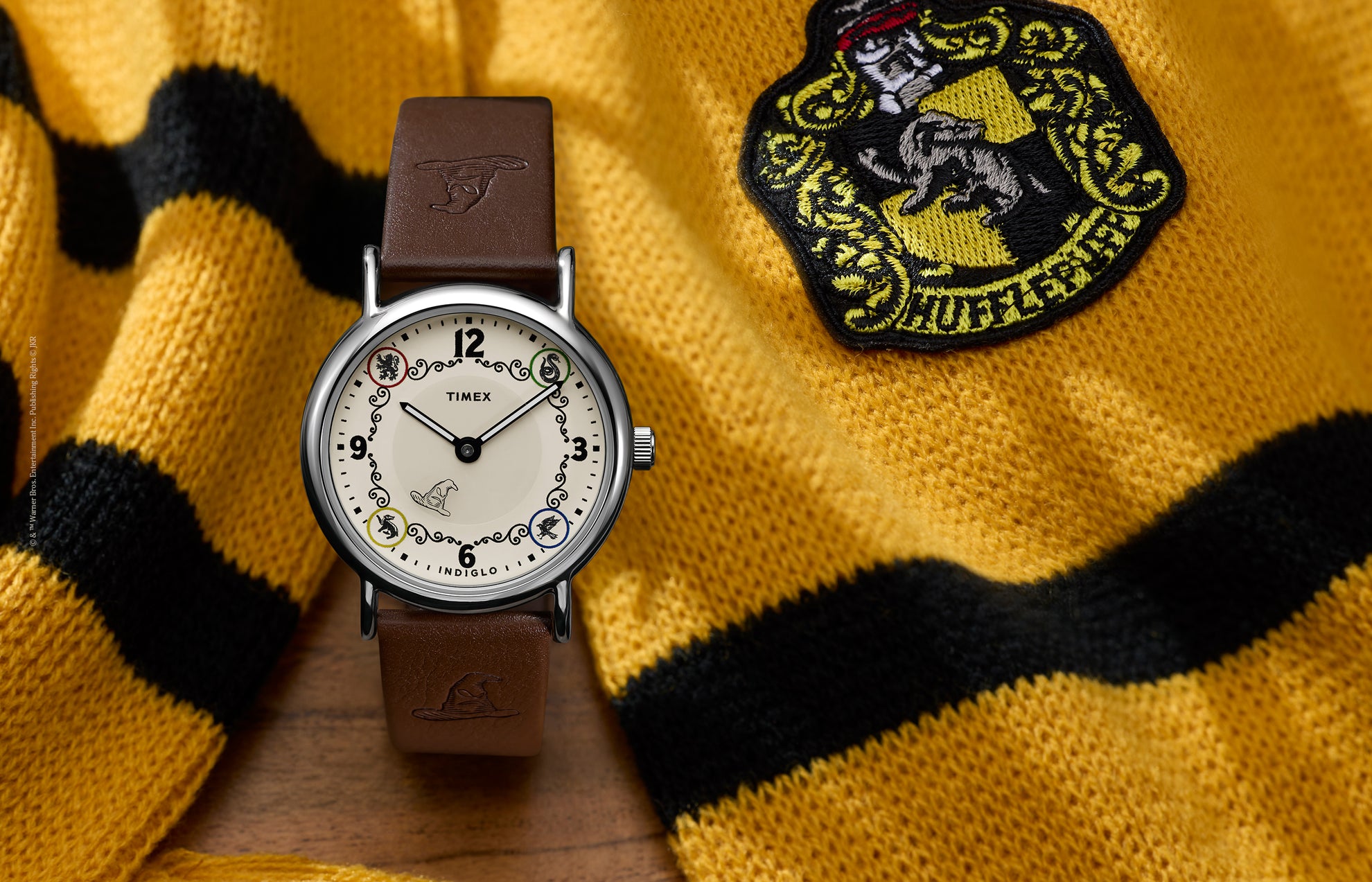 Harry Potter x Timex Weekender Hufflepuff House watch with brown leather strap displayed beside a yellow and black Hufflepuff scarf.