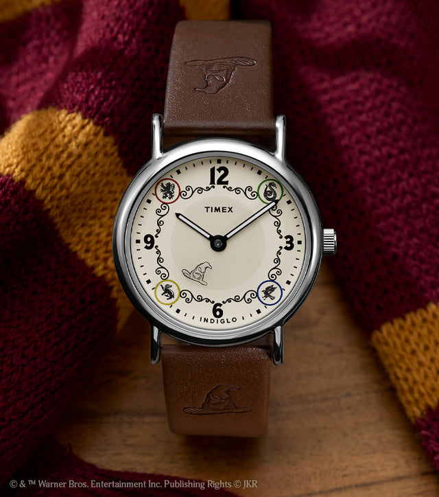 Harry Potter x Timex Weekender Gryffindor House watch with brown leather strap displayed beside a red and gold Gryffindor scarf.