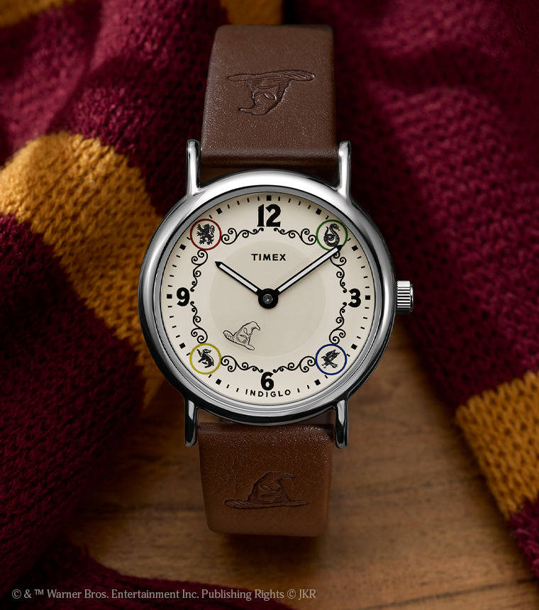 Harry Potter x Timex Weekender Gryffindor House watch with brown leather strap displayed beside a red and gold Gryffindor scarf.