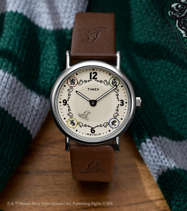 Harry Potter x Timex Weekender Slytherin House watch with brown leather strap displayed beside a green and silver Slytherin scarf.