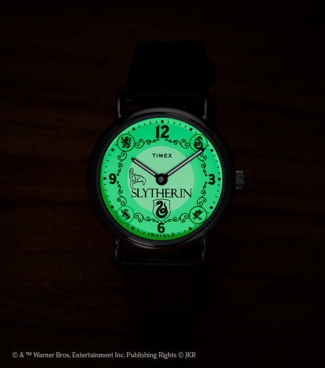 Harry Potter x Timex Weekender Slytherin watch illuminated in green INDIGLO mode showing Slytherin name and serpent crest.