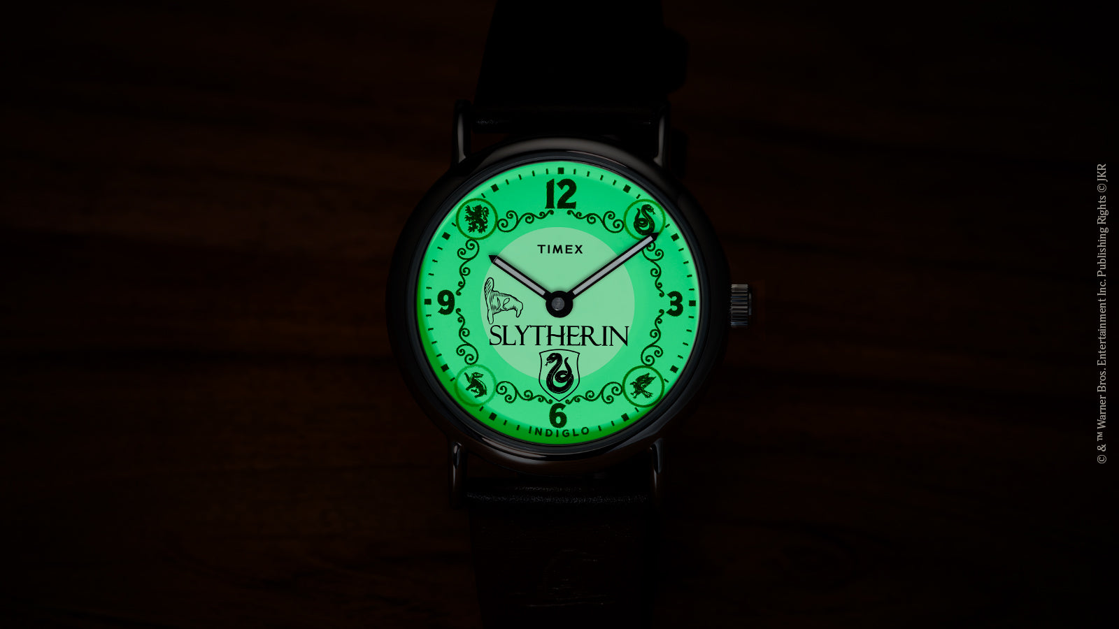 Harry Potter x Timex Weekender Slytherin watch illuminated in green INDIGLO mode showing Slytherin name and serpent crest.