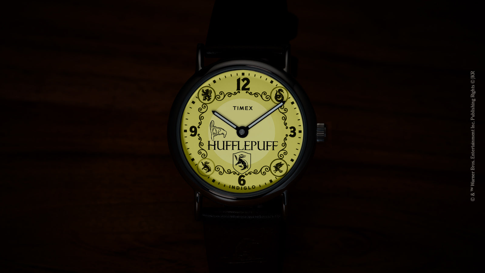 Harry Potter x Timex Weekender Hufflepuff watch illuminated in yellow INDIGLO mode showing Hufflepuff name and house crest.