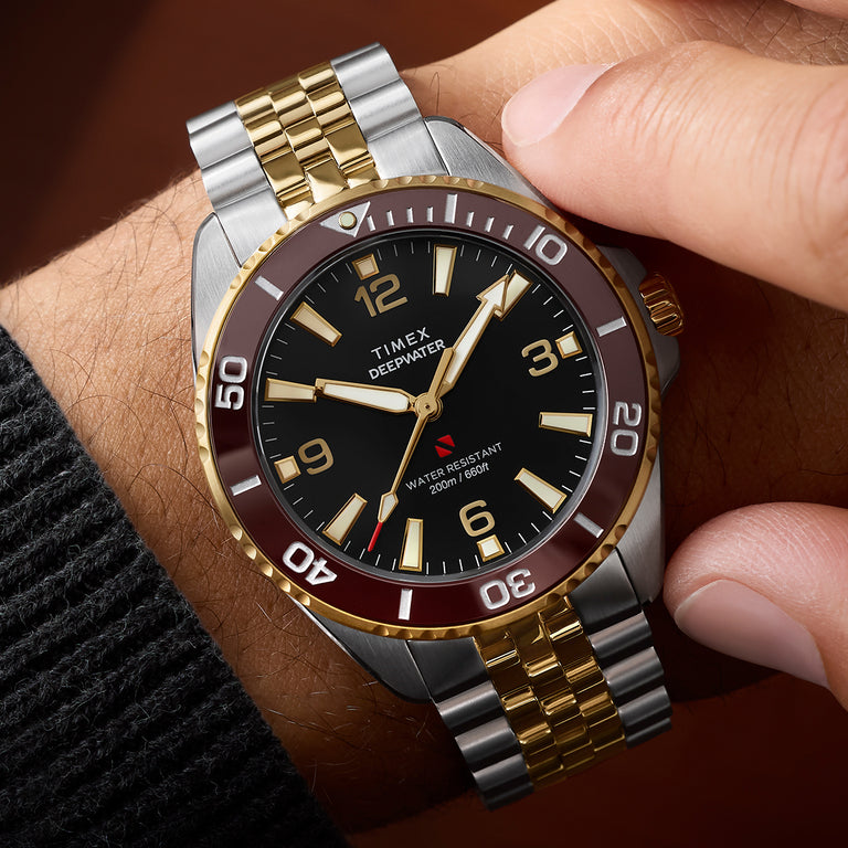 Timex Deepwater Arctic two-tone watch worn on wrist with burgundy bezel and gold center links