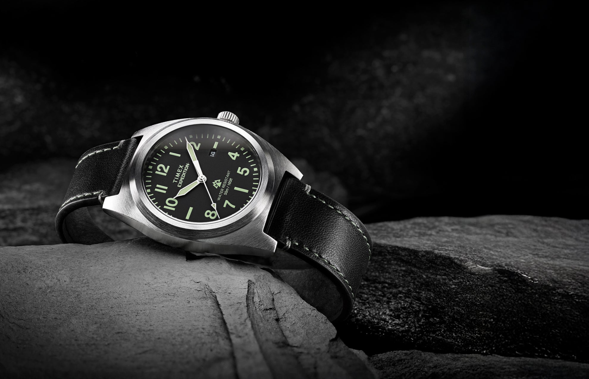 Timex Expedition Capstone watch with black dial and leather strap resting on rocks