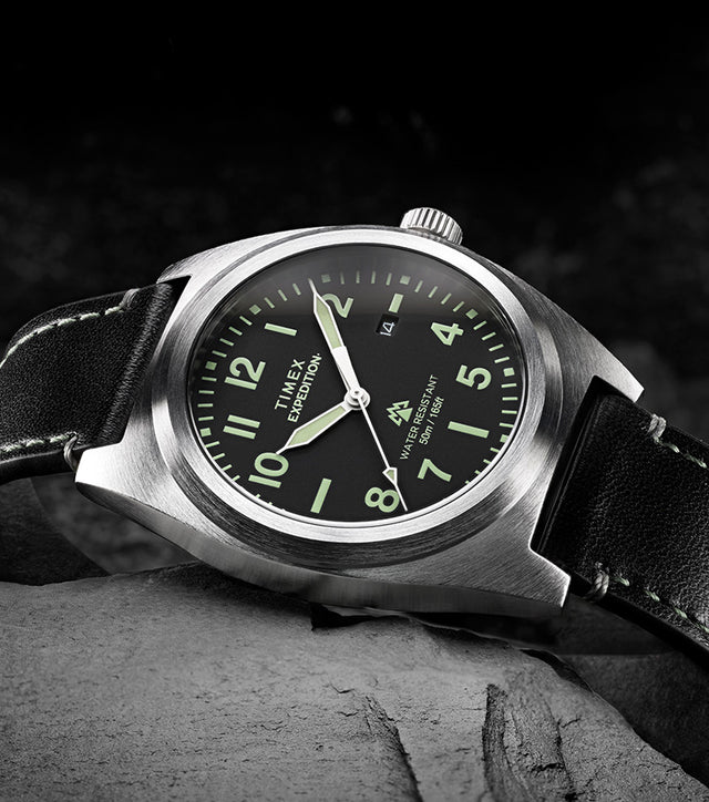 Timex Expedition Capstone watch with black dial and leather strap resting on rocks