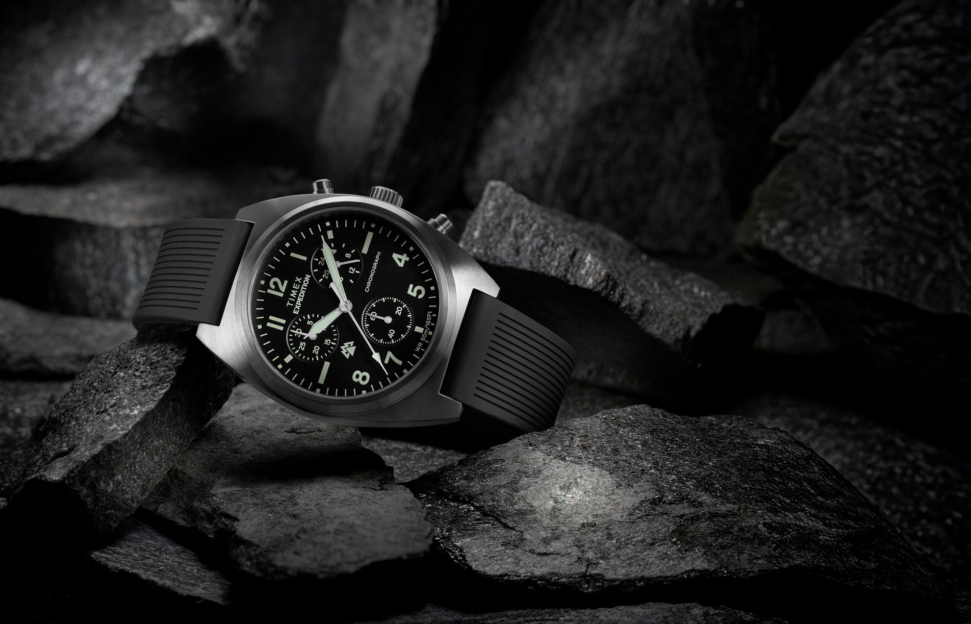 Timex Expedition Capstone Chronograph with black dial and rubber strap resting on rugged rocks