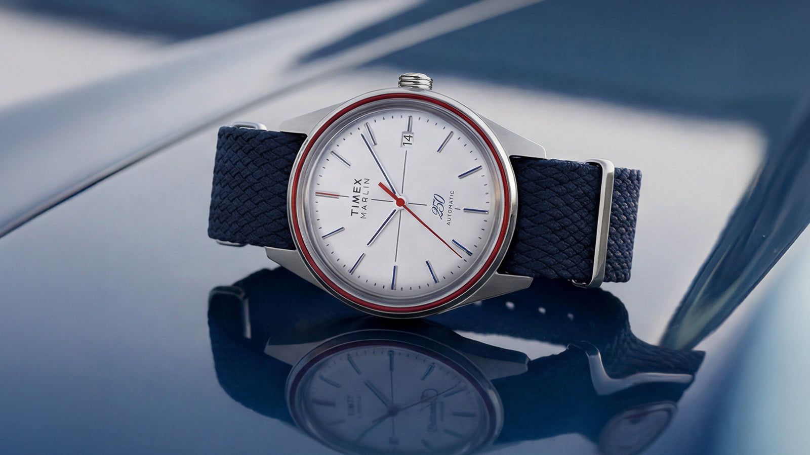 Marlin Jet America 250 automatic watch featuring a white dial, red accent ring, blue markers, and blue woven fabric strap.