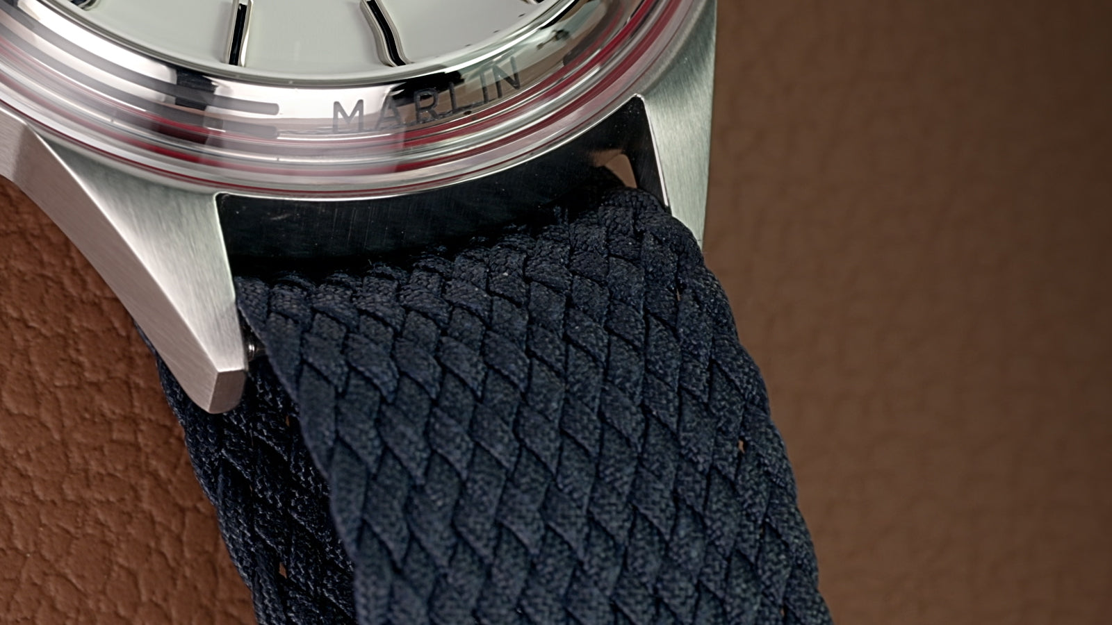 Close-up of the Marlin Jet America 250 blue woven strap and stainless-steel case with engraved Marlin branding.