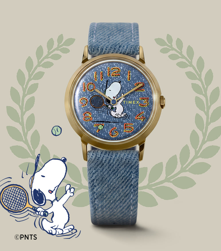 Peanuts® x Timex Marlin® 1965 Reissue Inspired Snoopy Tennis watch featuring a gold-tone case, blue denim-style strap, and Snoopy tennis artwork on the dial.