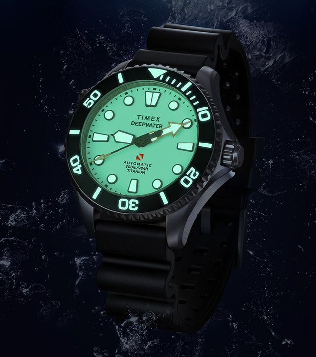 Timex Deepwater Meridian 300 Titanium HEV Automatic dive watch with full-lume dial and black rubber strap suspended in an underwater scene with rising bubbles.