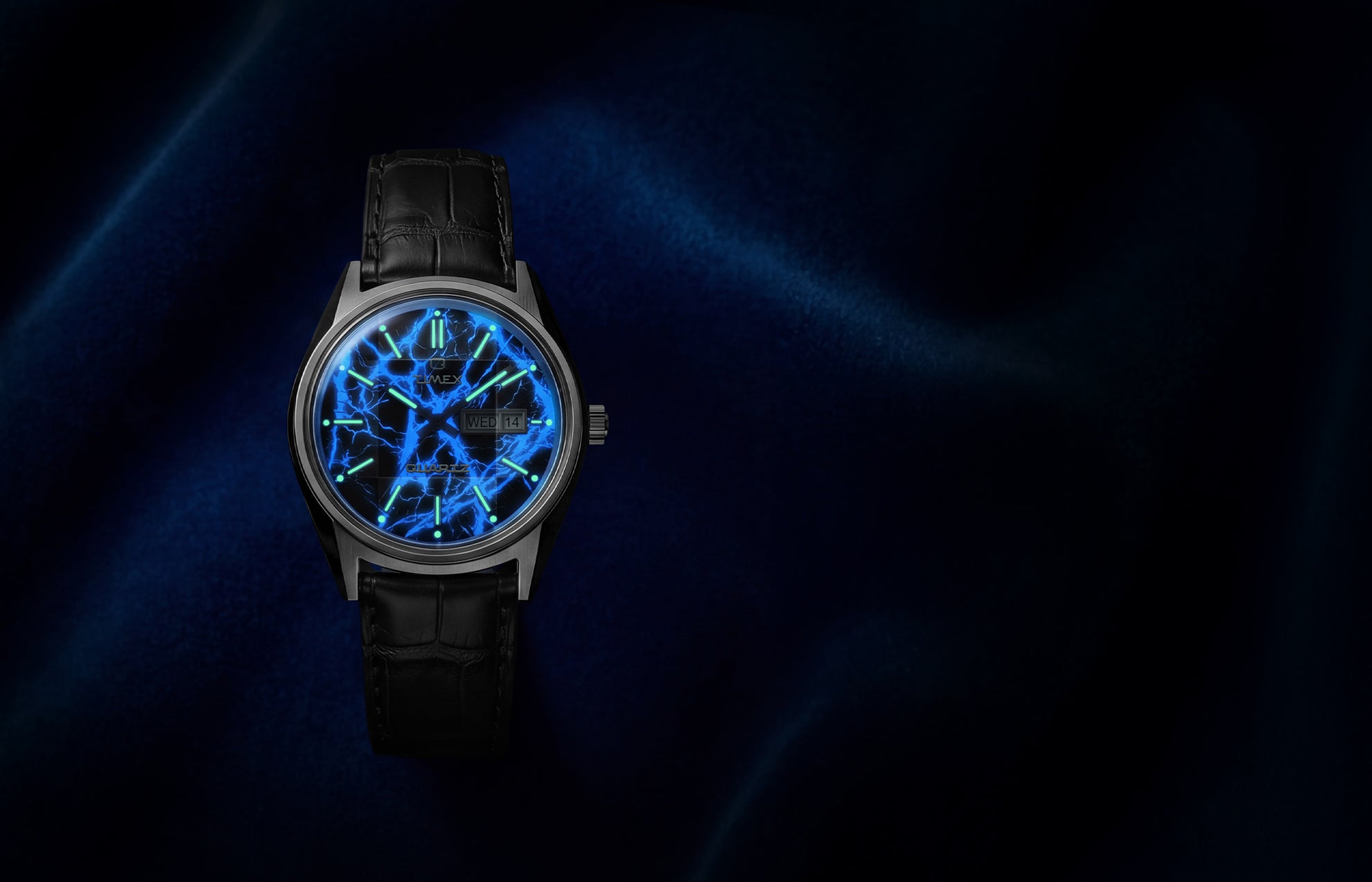 Q Timex Blue Vega watch glowing in the dark with illuminated blue lightning dial and lume hour markers on black leather strap