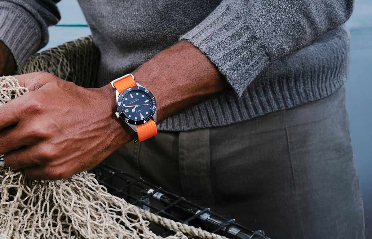 Man wearing the Bespoke Post x Timex Heritage 66 watch with a bright orange strap.