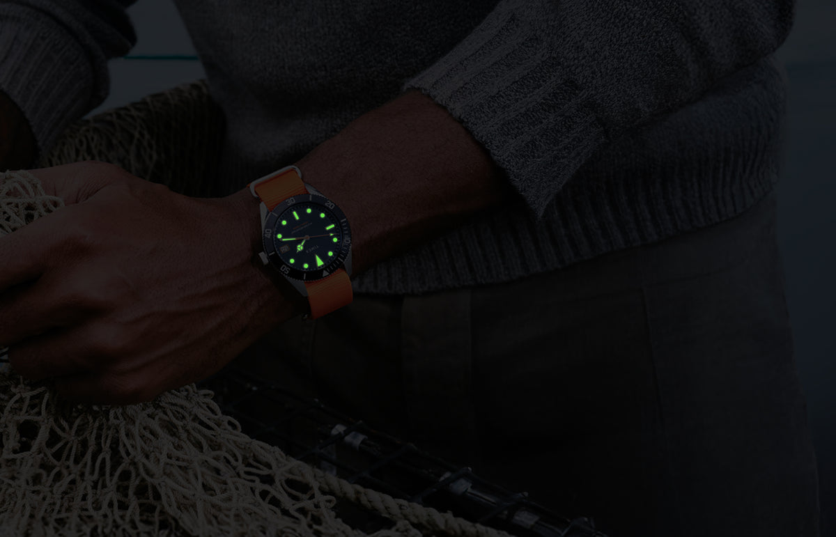Bespoke Post x Timex Heritage 66 watch glowing in the dark on a man’s wrist.