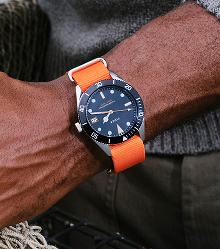 Man wearing the Bespoke Post x Timex Heritage 66 watch with a bright orange strap.