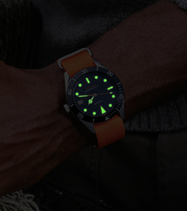 Bespoke Post x Timex Heritage 66 watch glowing in the dark on a man’s wrist.