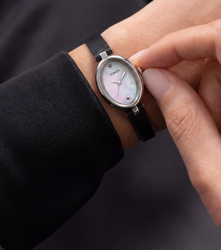 Reloj Timex Cavatina® Luxe en tono plateado, con esfera de nácar y correa de piel negra, lucido en la muñeca.