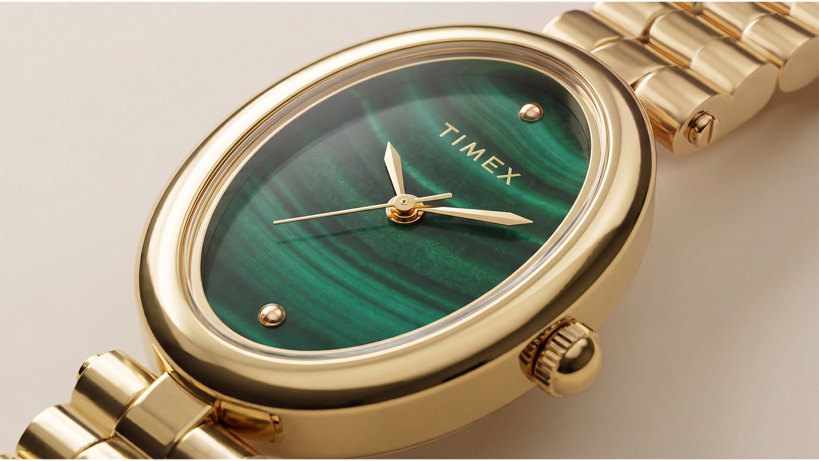 Close-up of the Timex Cavatina® Luxe showcasing a polished gold-tone oval case, green malachite-pattern dial, and minimalist gold-tone hands.