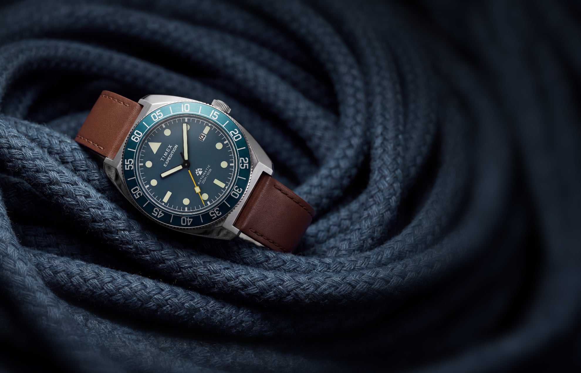 Timex Expedition Pioneer Automatic with a blue dial, blue rotating bezel, and brown leather strap displayed on coiled navy rope.