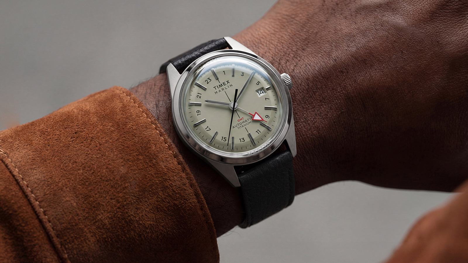 Timex Marlin® Jet Titanium Automatic GMT on wrist with cream dial, date display, red GMT hand, and black leather strap.